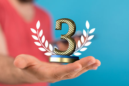 A shallow focus shot of a human hand holding third place prize - competition concertの写真素材