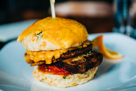 A closeup shot of the breakfast biscuit sandwich on the white plate on the blurry backgroundの写真素材