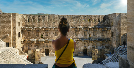 A photo of a back of a white Caucasian girl sitting in Aspendos Theatre, Antalya, Turkeyの写真素材