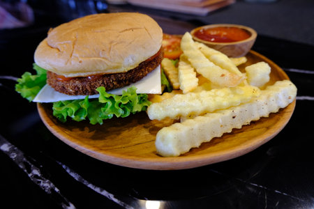 A closeup of a delicious burger with crinkle-cut fries and ketchup on a tray at a restaurant