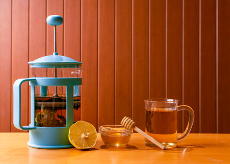 A herbal tea in a teapot next to a cup, lemon and honey.の写真素材
