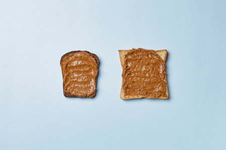 A slice of brown bread and a toast buttered with tasty peanut butter over the blue surfaceの写真素材