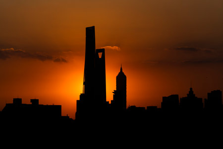 A beautiful shot of an orange sun setting near modern buildingsの写真素材