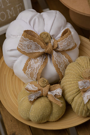 A photo of fabric pumpkins of white and beige colors with twine cord and on a wooden tableの写真素材