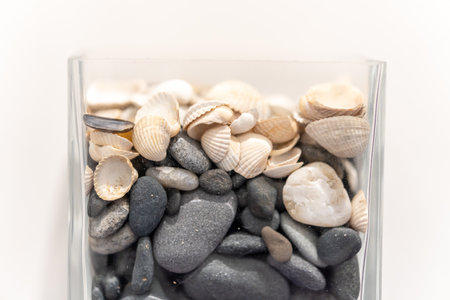 A transparent jar of seashells and small rocks