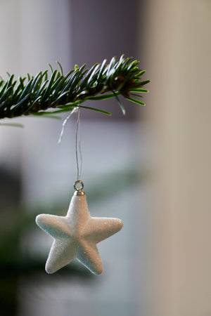 A vertical shot of a star ornament hanging on a Christmas tree
