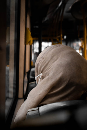 A rear view of a female wearing brown hijab sitting in a bus