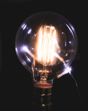 A selective focus of an illuminated light bulb lit in the darknessの写真素材