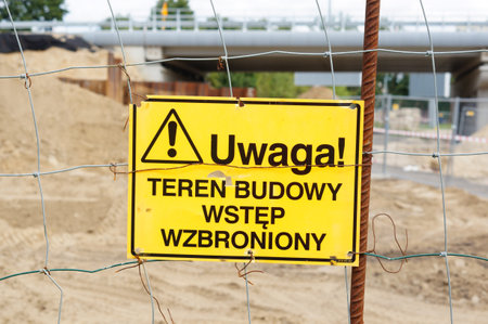 A closeup of a yellow danger warning construction sign on a metal barricade