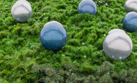 A textured surface made of green pine needles, a part of a Christmas tree, balls and a luminous garland.の写真素材