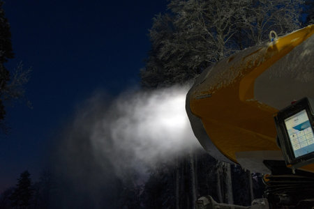 Night time photo of snow cannon or artificial snowmaking machine in action on a cold winter day in...