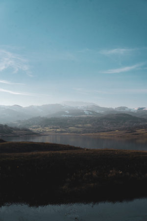 A peaceful scene with a lake and silhouette of hills in the background