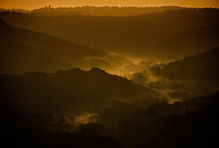 A landscape of hill silhouettes during a breathtaking sunset in the evening in Tuscany, Italyの写真素材