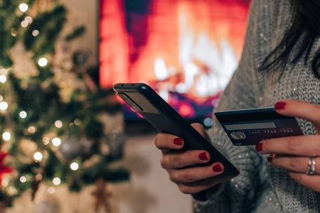 Hand holding credit card, paying online on mobile phone, buying christmas presents.の写真素材