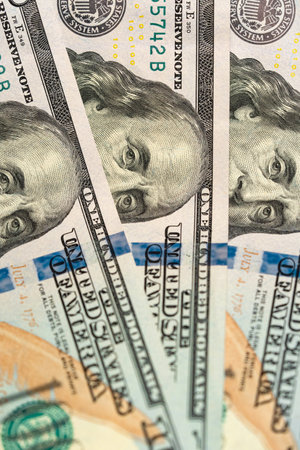 A vertical, close-up shot of a 100 dollar bill with the face of Benjamin Franklin