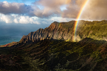 A landscape of the Waimea Canyon State Park surrounded by the sea with a rainbow over it in Hawaiiの写真素材