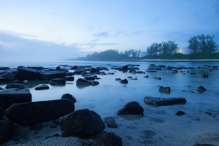 A landscape of a lake surrounded by rocks and a forest covered in the fog in the eveningの写真素材