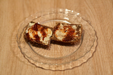 A closeup of bread with butter and strawberry marmalade spread on it