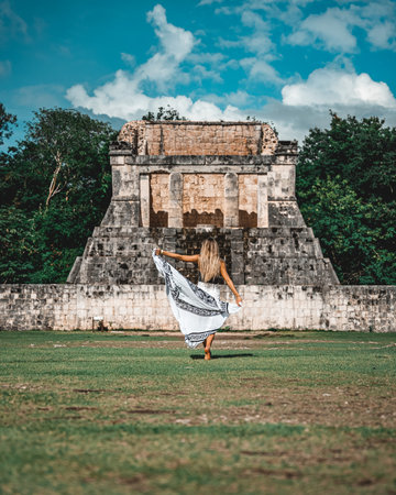 A vertical shot of a young caucasian female standing against the Chichen Itza, Mexico