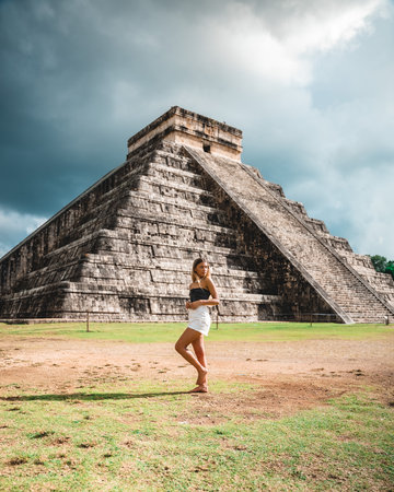 A vertical shot of a young caucasian female standing against the Chichen Itza, Mexico