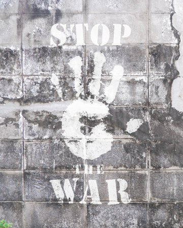 A vertical shot of an old concrete wall of a building outdoors with a Stop