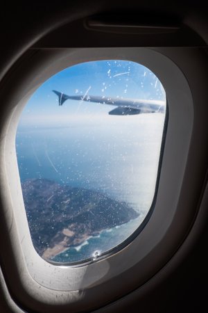 A vertical shot through the window of an airplane on an island.の写真素材