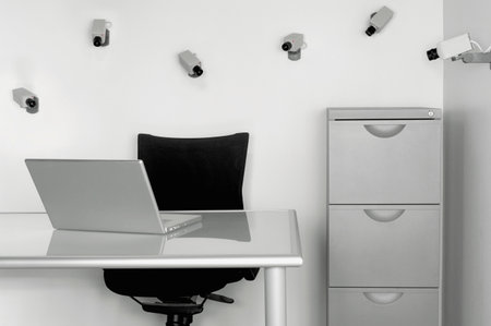 A closeup of a gray laptop on the desk in a room with many cameras