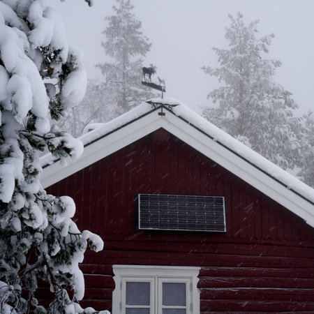 A snow-covered Norwegian off-grid cabin with solar panel in snowy weatherの写真素材