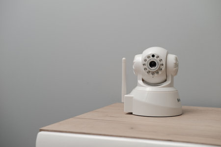 A closeup of a white wireless IP camera on a wooden surface