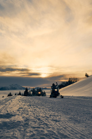 A people riding sledges at the foot of the mountain with yellow sunset on the backgroundの写真素材