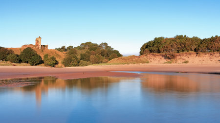 A beautiful landscape of the Lunan Bay Castle with reflection at high tide, Angus, Scotland