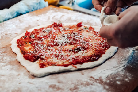 A photo of a person's hands preparing pizza on a wooden board