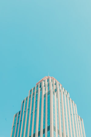 A vertical shot of the modern office building against the blue sky.