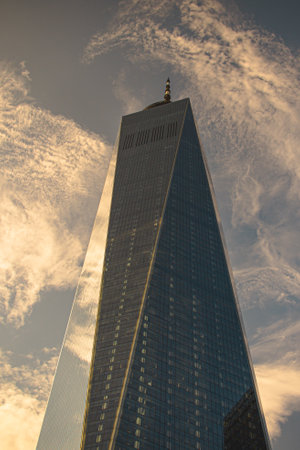 A vertical shot of a sky tower in reflecting the cloudy sky in New York.