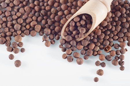 A closeup shot of black pepper pile with wooden spoonの写真素材