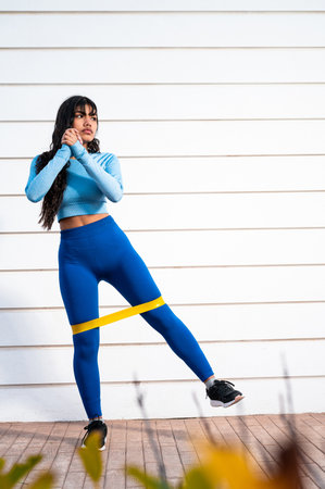 A Attractive Colombian woman dressed in sportswear, doing physical exercises in a park