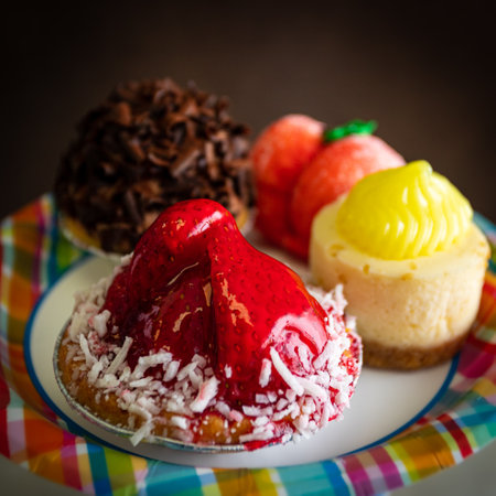 A square selective focus shot of a strawberry tart on a colorful plate with a variety of dessertsの写真素材