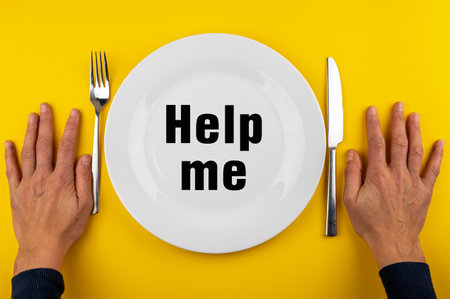 A photo of man's hands with fork, knife and empty plate with the words help