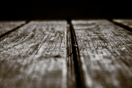A shallow focus of an old wooden texture surface in greyscale on a black background