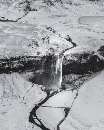 A vertical shot of a mesmerizing snowy landscape with a waterfall in Icelandの写真素材