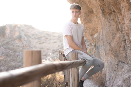 A Caucasian man leaning on the wooden railing on the mountain