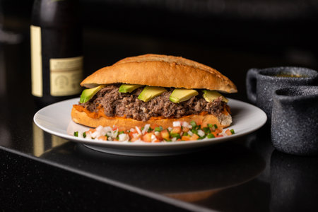 A fresh sandwich on a plate with ground beef and avocado.の写真素材