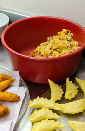A vertical closeup of freshly fried dumplings on a tissue against a bowl of stuffing