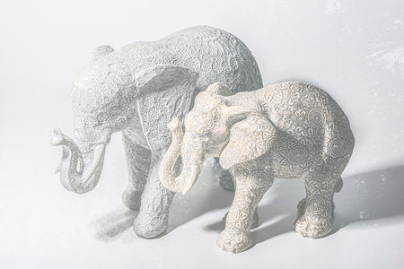 Two elephants on horizontal white background, religious objects.