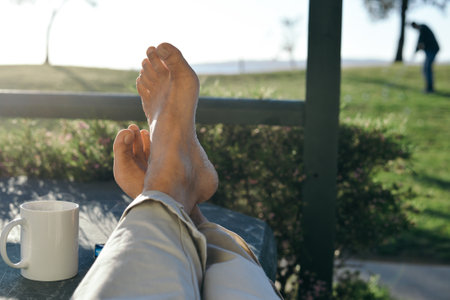 The closeup of person's feet while resting in the park on a sunny day with blurred background