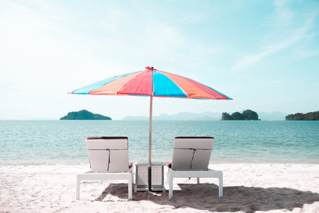A colorful summer umbrella with chairs under it on the seashore on a clear day