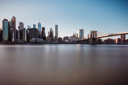 A stunning view of New York City, modern skyscrapers and the Brooklyn Bridge under a cloudless sky