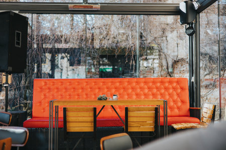An interior of a cafe with an orange couch and glass walls surrounded by trees on a winter dayの写真素材