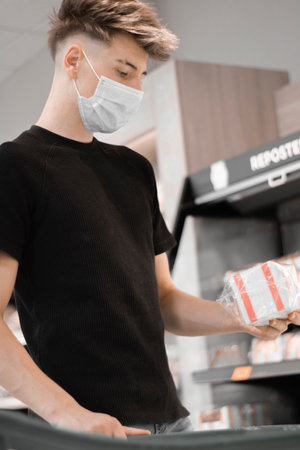 A vertical shot of a Caucasian boy wearing a medical mask, shopping for groceriesの写真素材