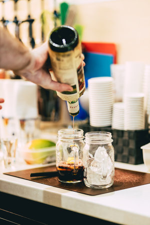 A vertical shot of a bartender making mango and grape-flavored lemonades.